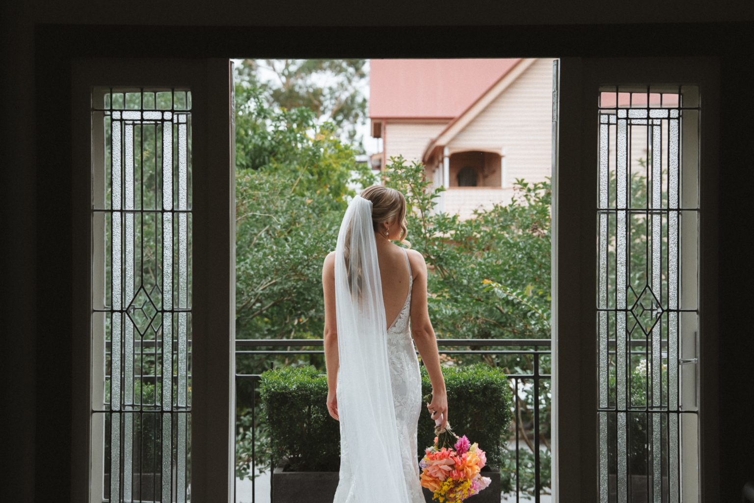 Bride standing in the balcony doorway with her bouquet