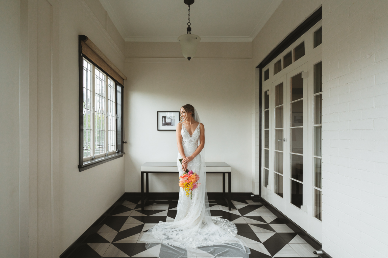 Bride on the patterned tile floor of a heritage hallway