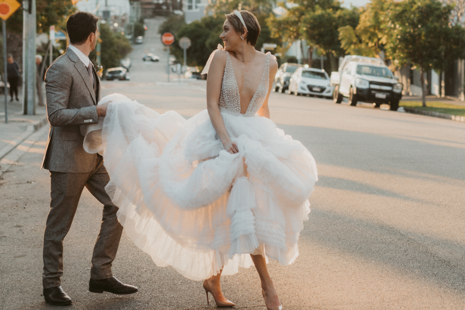 Groom holding the bride's tulle gown as they cross a Potts Point street