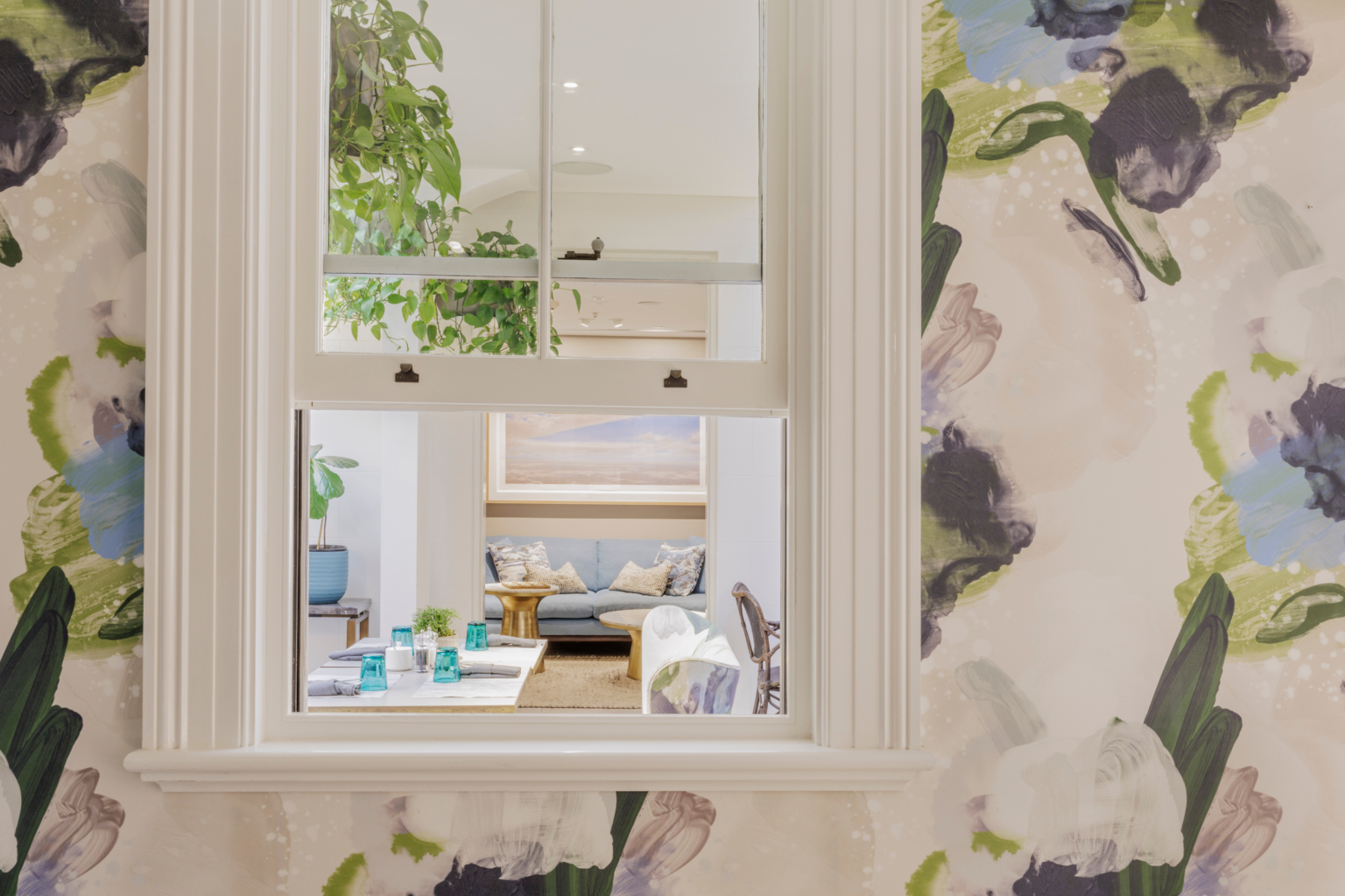 Window view into a suite framed by floral wallpaper
