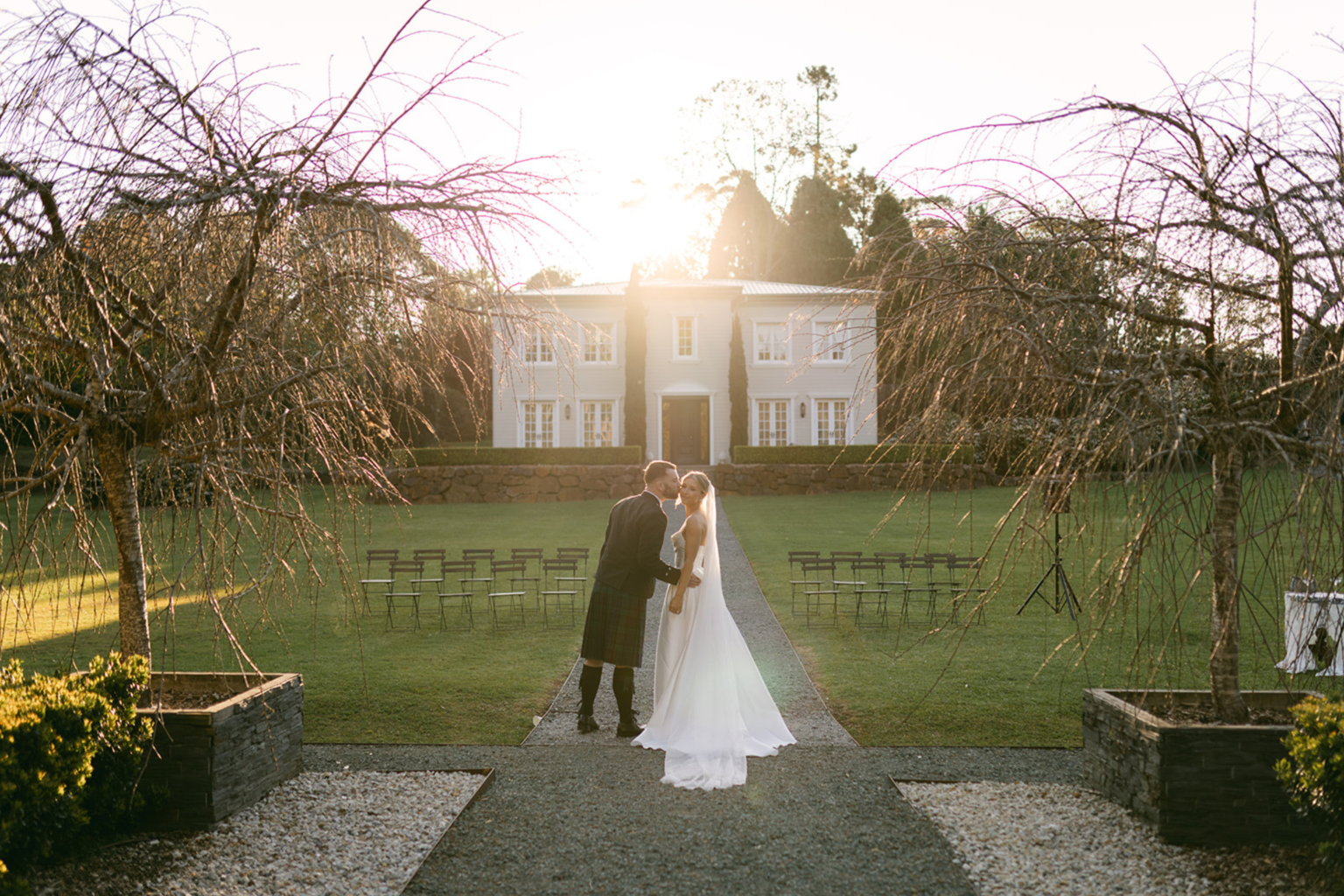 Couple kissing in the French Garden with the manor behind