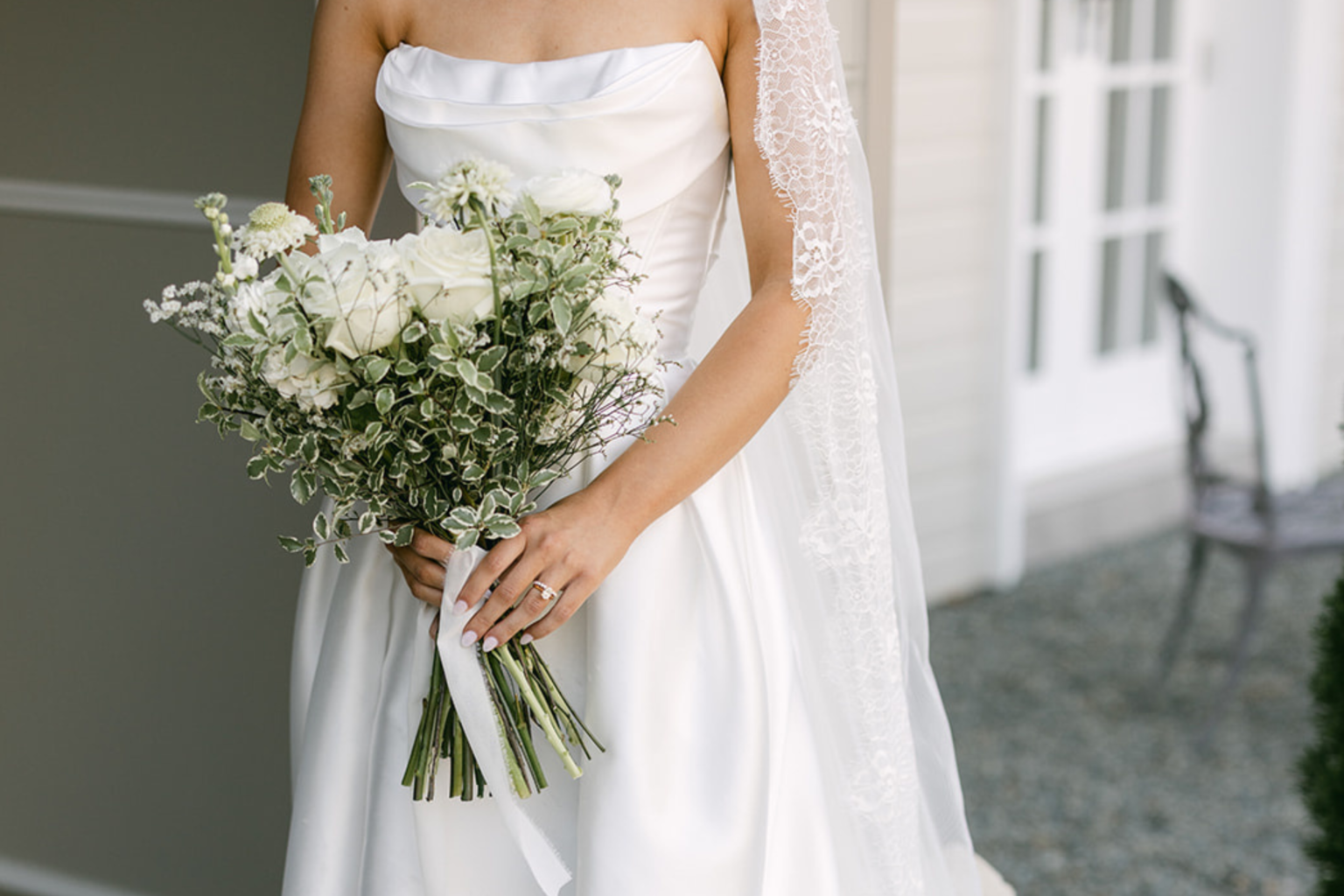 Bride holding a white bouquet beside the manor