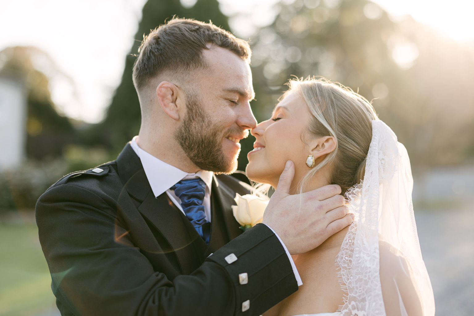 Bride and groom in a kilt nose to nose in golden light