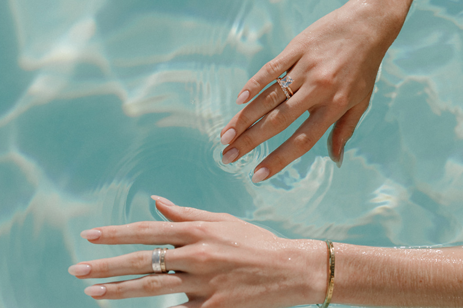 Hands with wedding rings trailing in the pool water