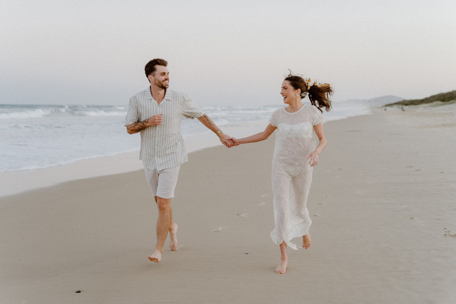 Couple running hand in hand along the beach at Port Stephens