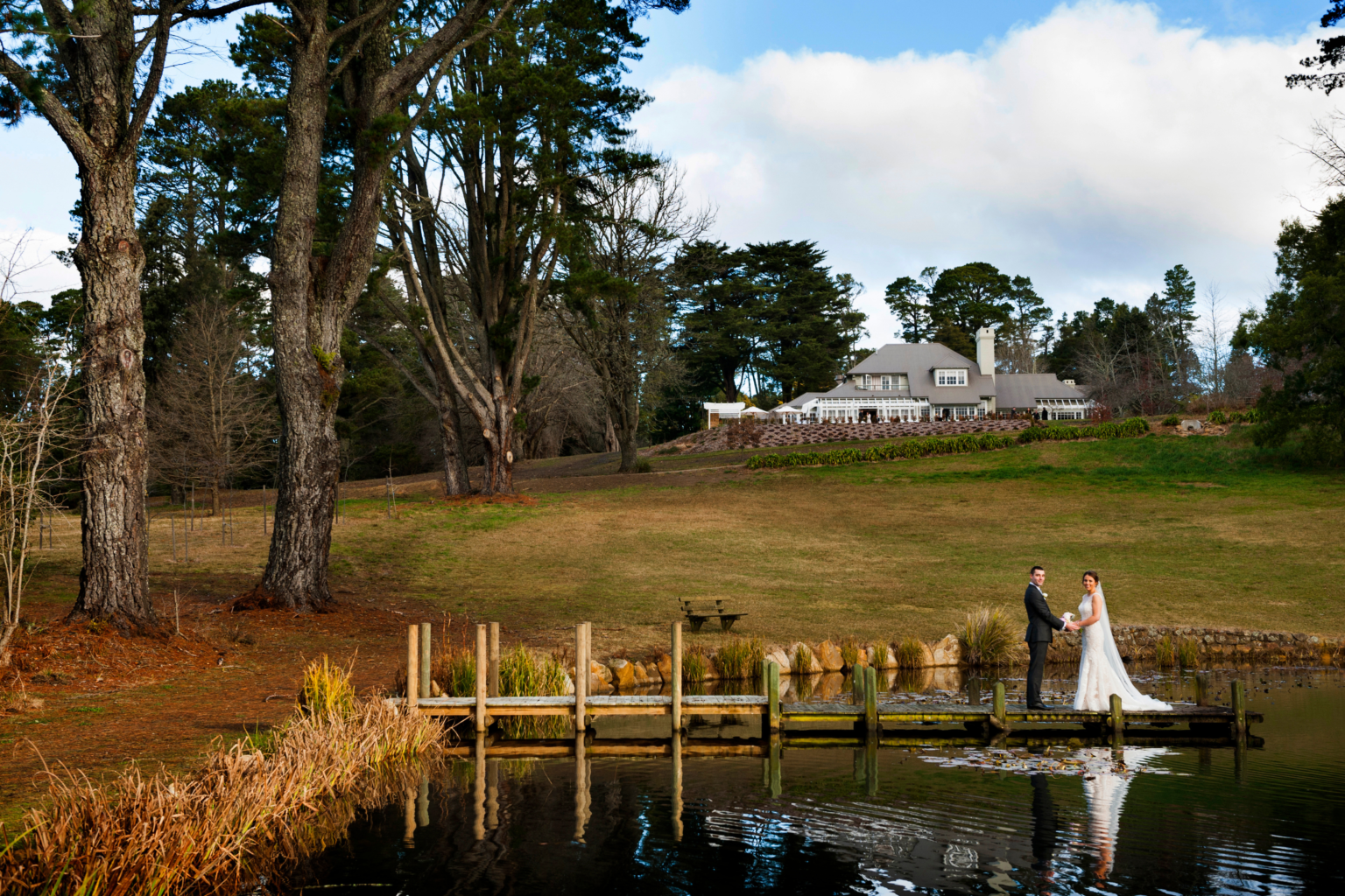 Couple on the lakeside jetty with the lodge in the distance, Parklands