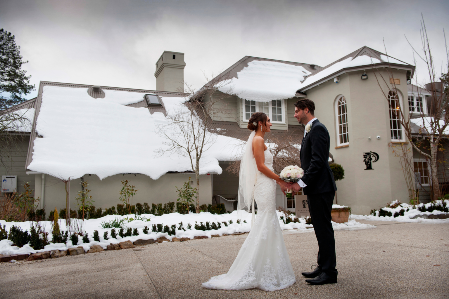 Couple in front of the snow-covered lodge at Parklands in winter