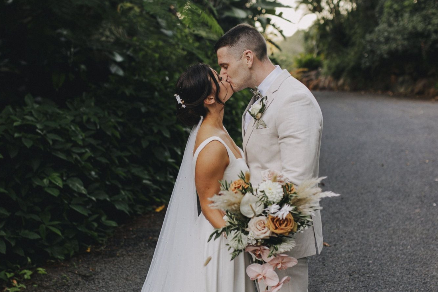 Bride and groom kissing on a rainforest path at Rainforest Gardens
