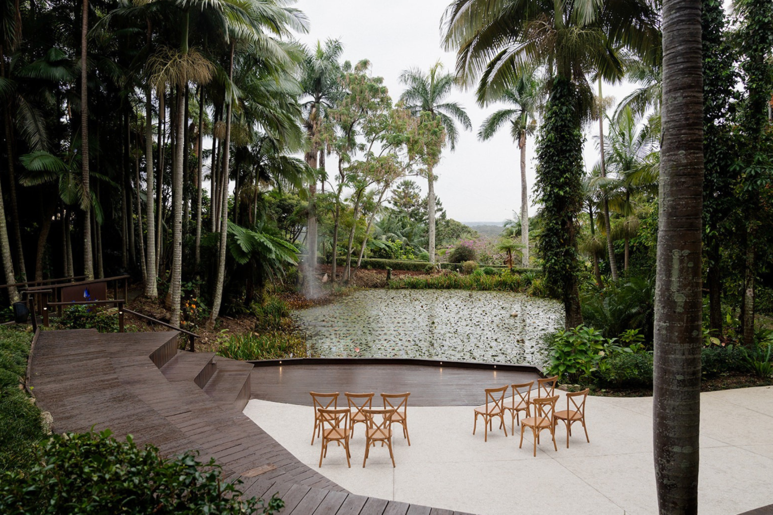 Lake deck with ceremony chairs among tall palms at Rainforest Gardens
