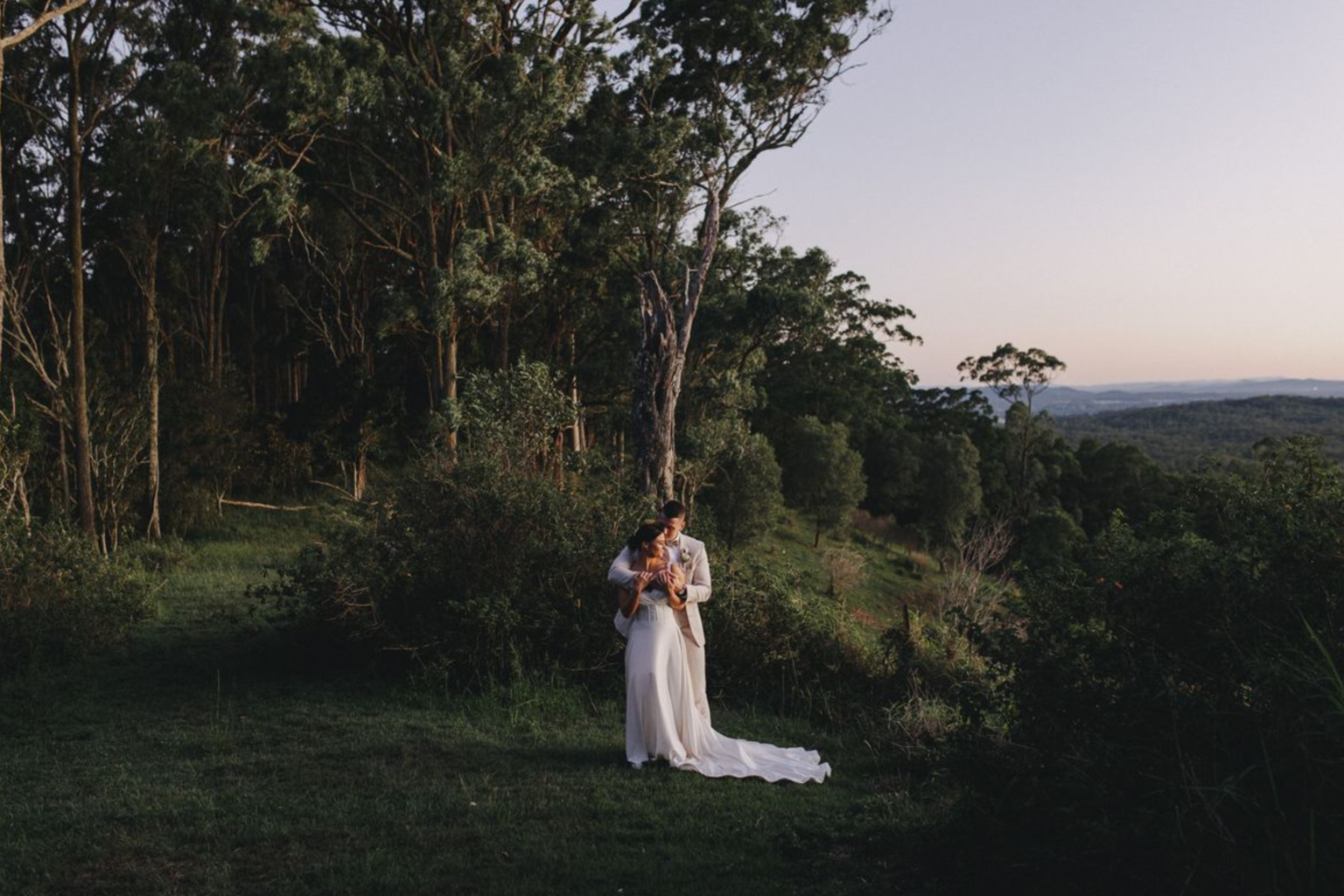 Couple embracing at the edge of the rainforest at dusk