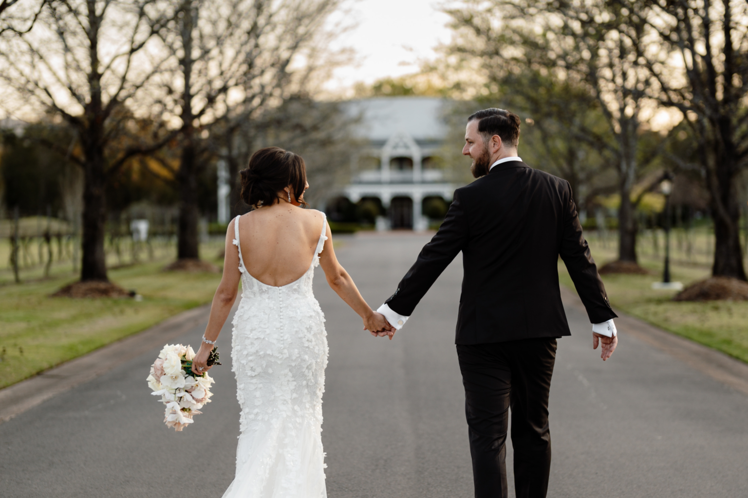 Bride and groom walking hand in hand up the drive at The Convent