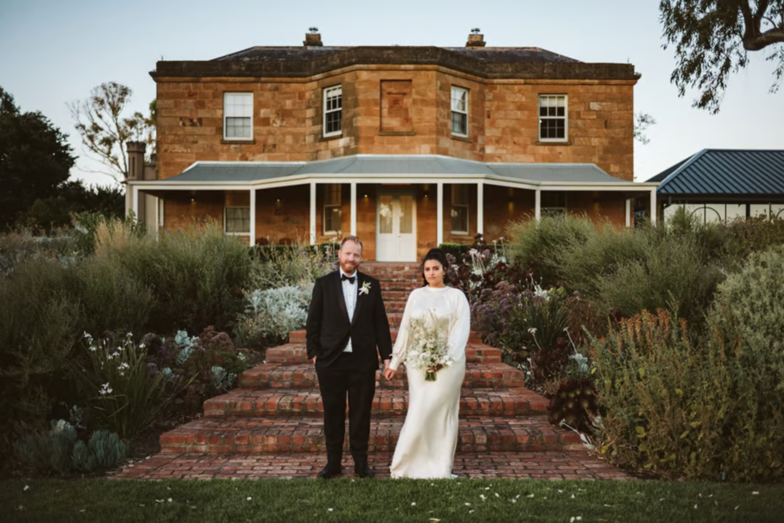 Bride and groom on the garden steps of the Kingsford homestead