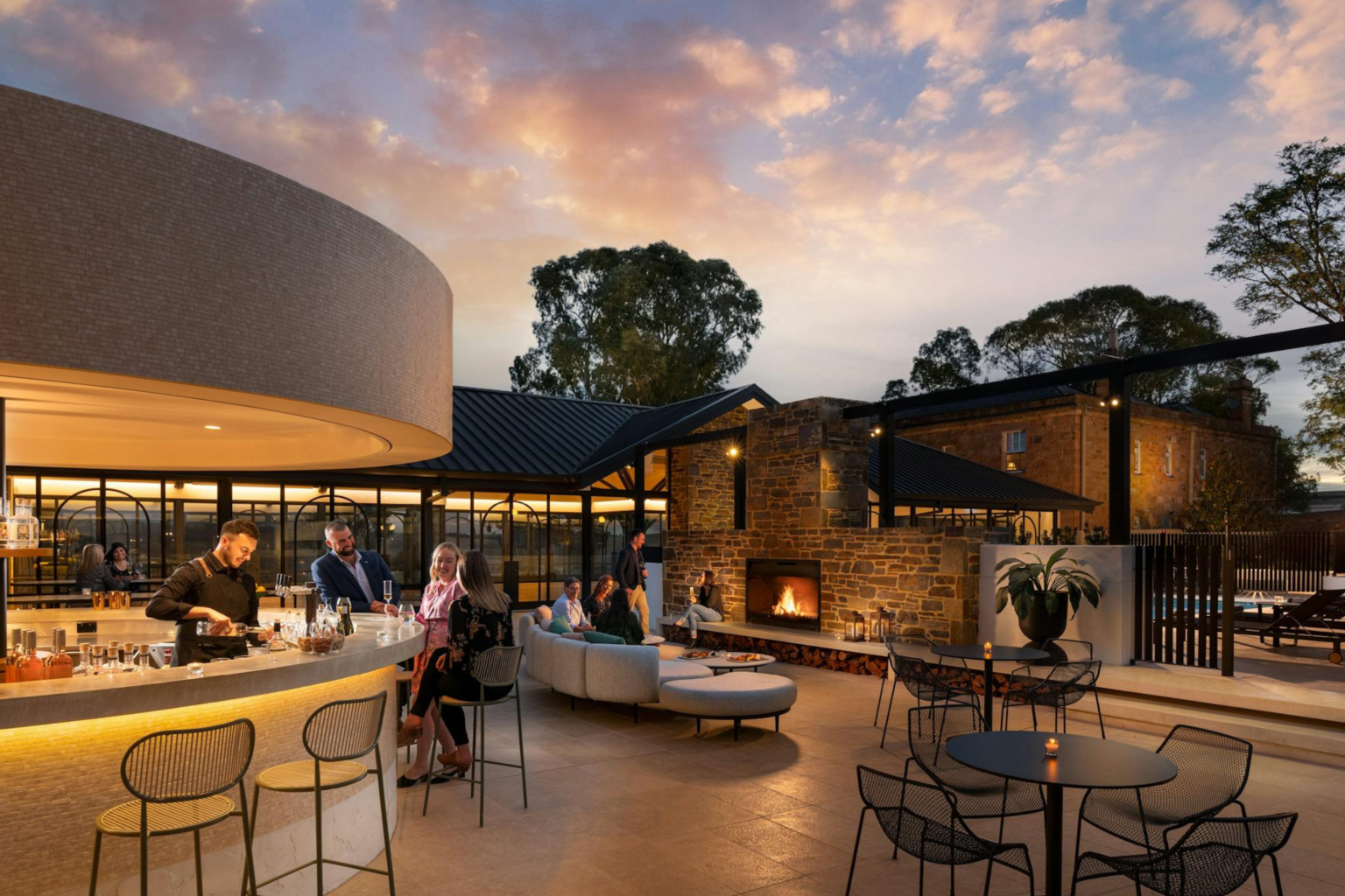 Guests at the bar beside an open fire at Kingsford The Barossa