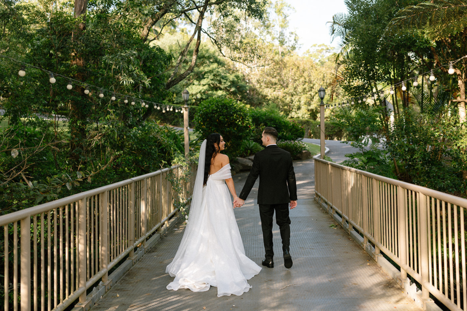 Bride and groom walking across the timber footbridge at Coolibah Downs