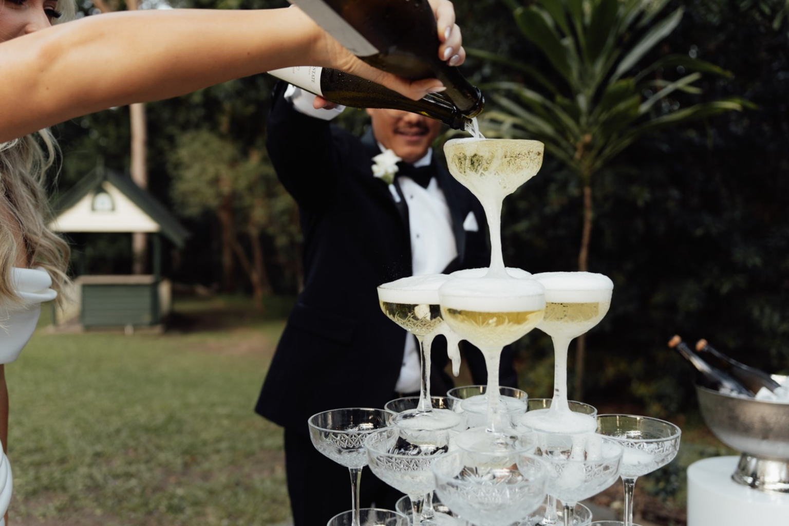 Groom pouring the champagne tower on the lawn