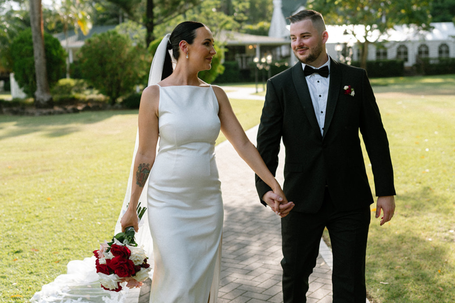 Bride and groom walking hand in hand across the lawn at Coolibah Downs