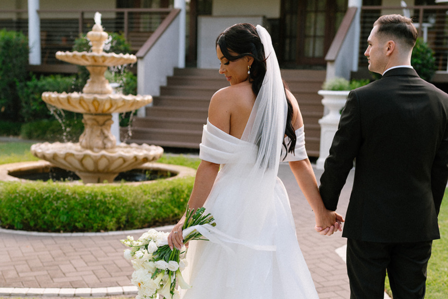 Couple walking past the fountain toward the homestead steps