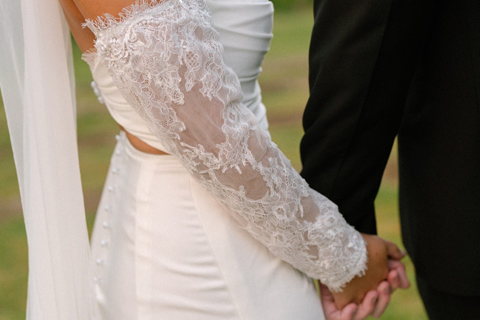 Close-up of the bride's lace sleeve as the couple hold hands