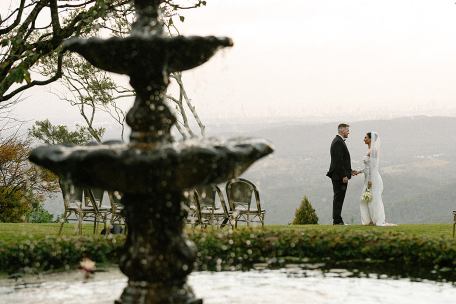 Couple standing beyond the fountain with views over the hinterland