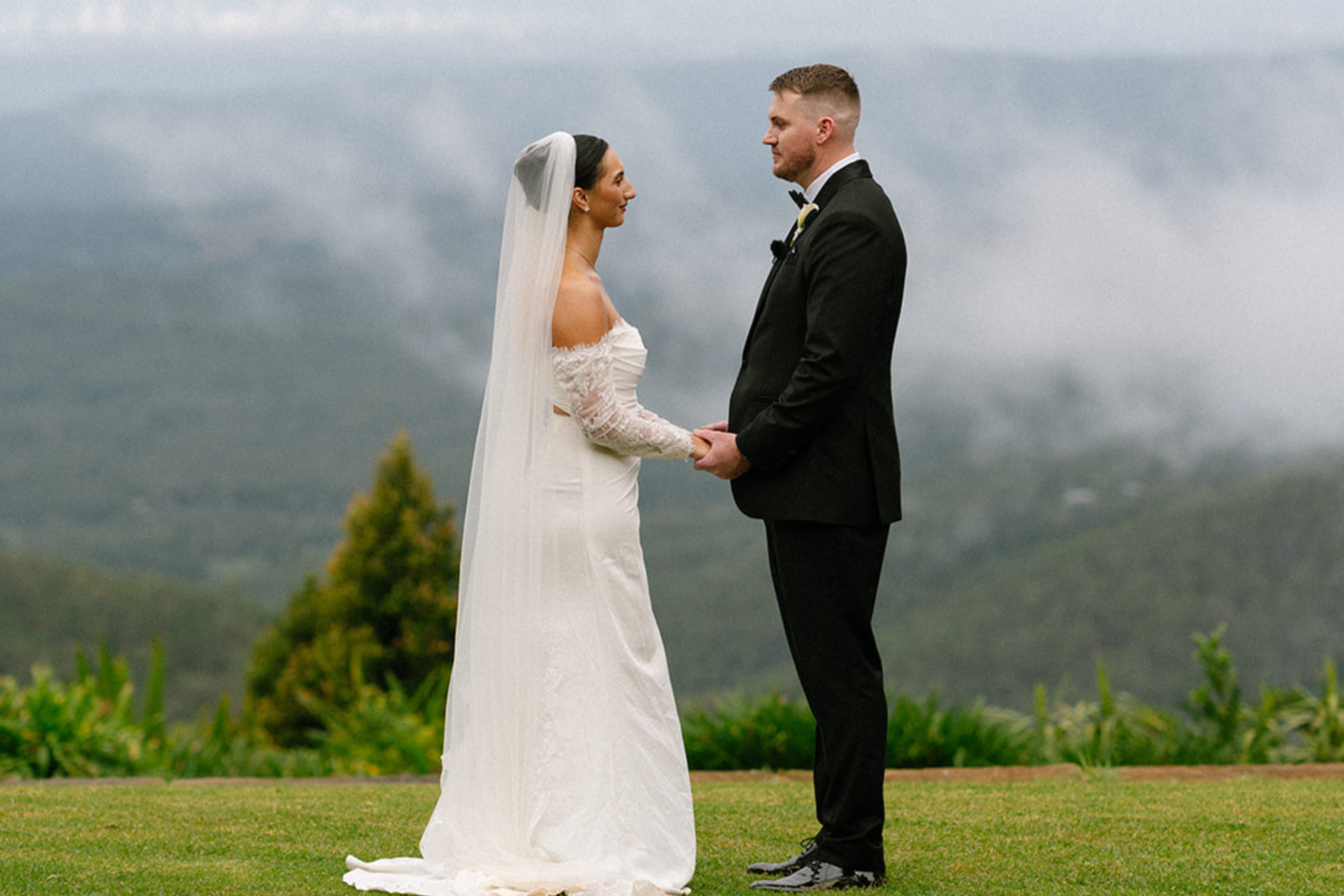 Bride and groom exchanging vows with misty mountain views