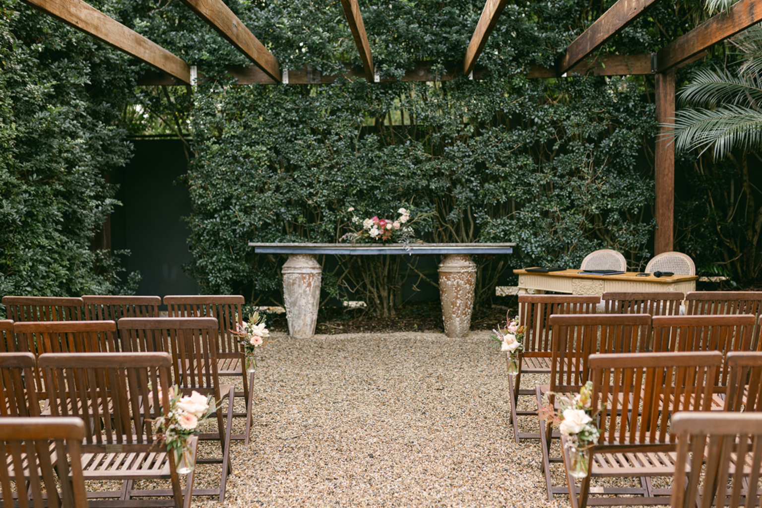 Courtyard Garden ceremony setting with timber chairs and stone altar