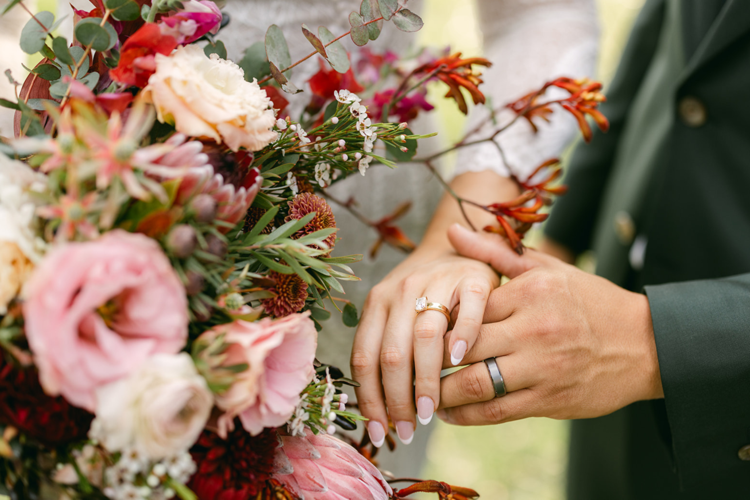 Couple holding hands with a pink and red bouquet
