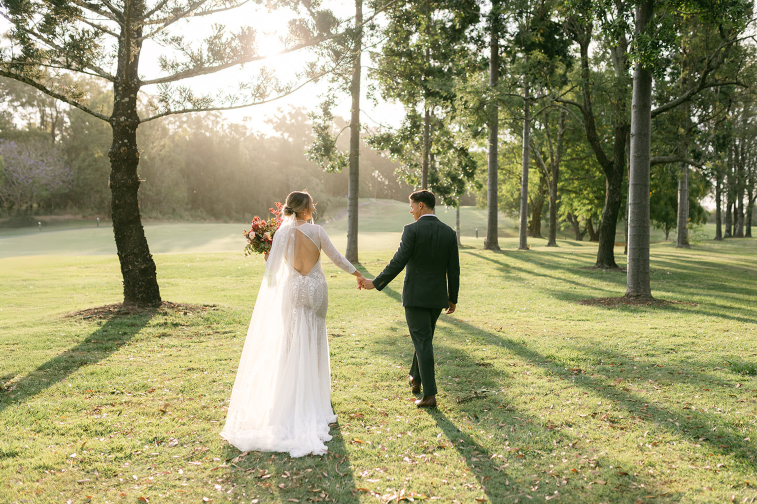 Bride leading the groom across the sunlit lawn