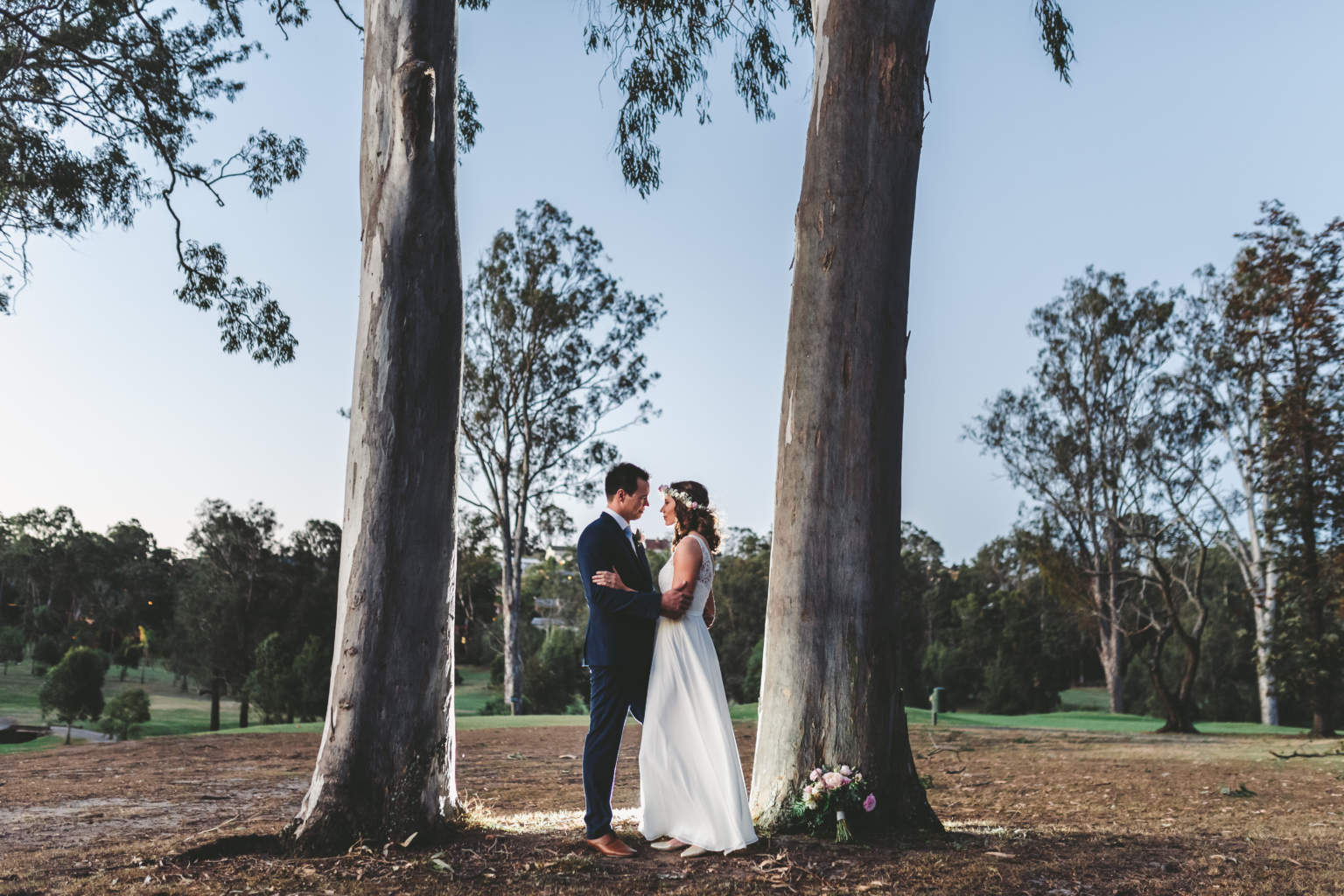 Couple standing between two tall gum trees on the course