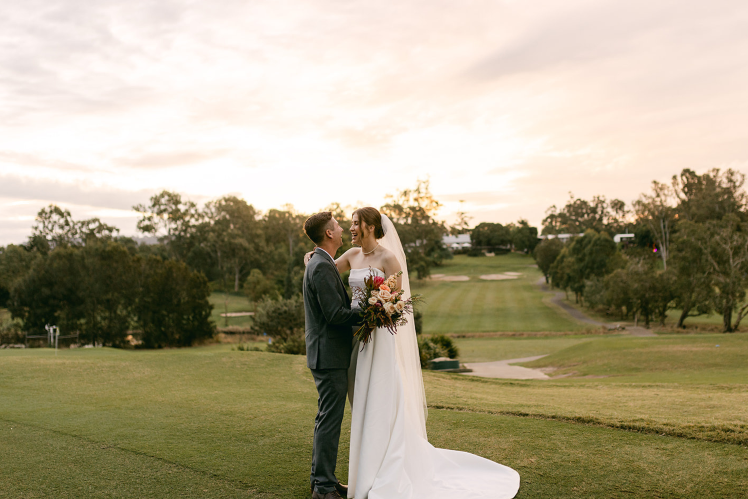 Couple embracing on the golf course at sunset