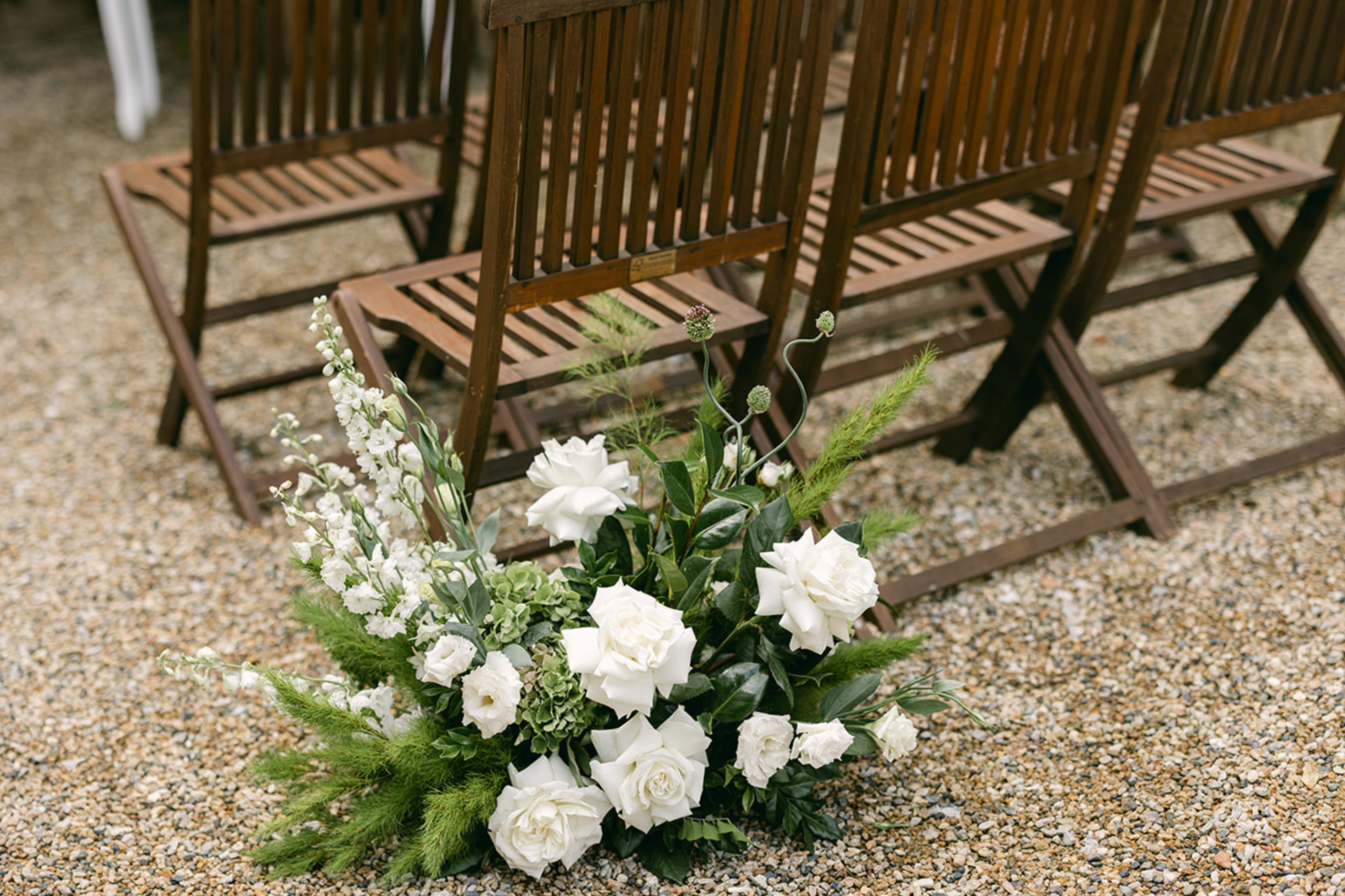 Timber ceremony chairs with white floral arrangements