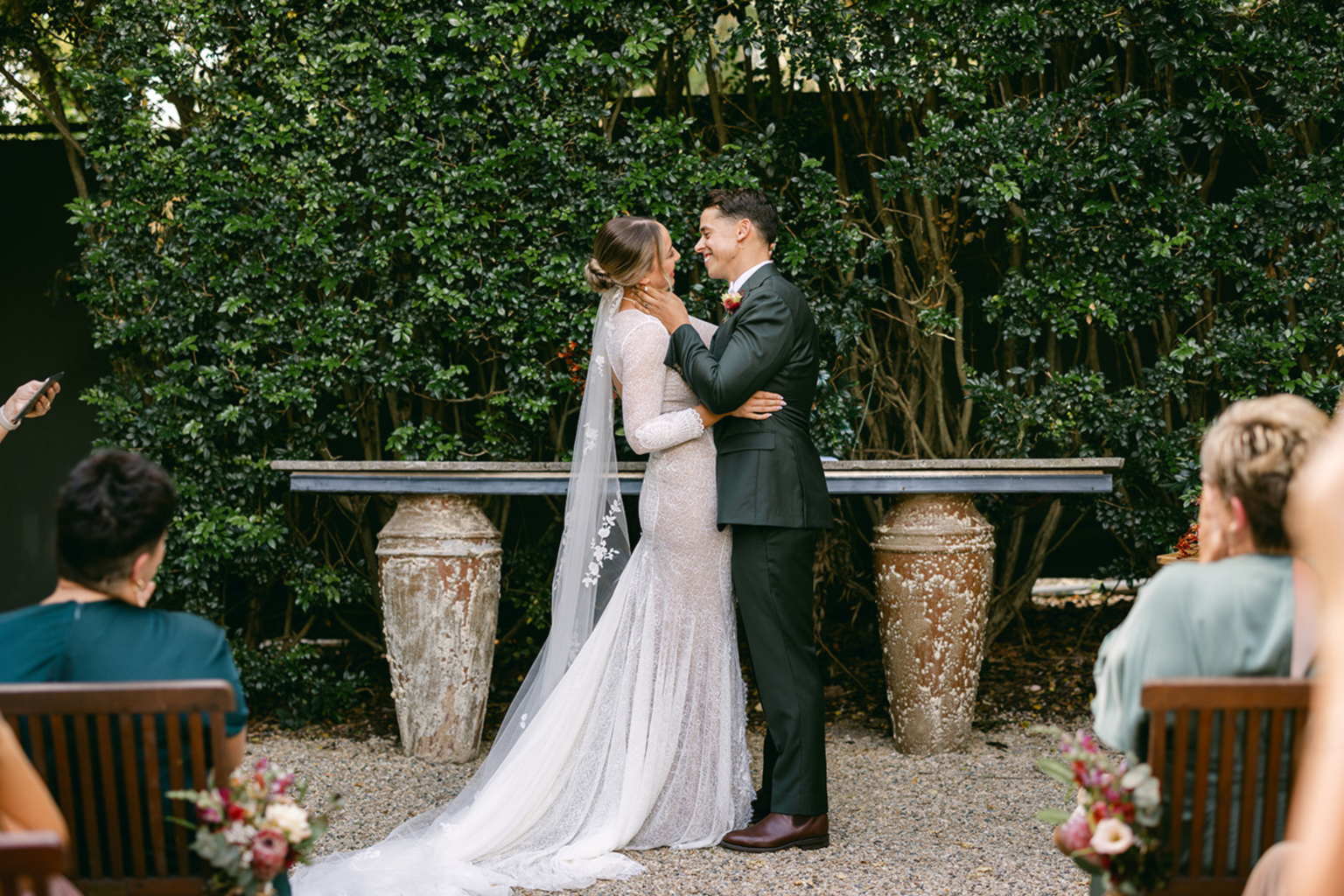 Bride and groom embracing at the stone altar in the Courtyard Garden