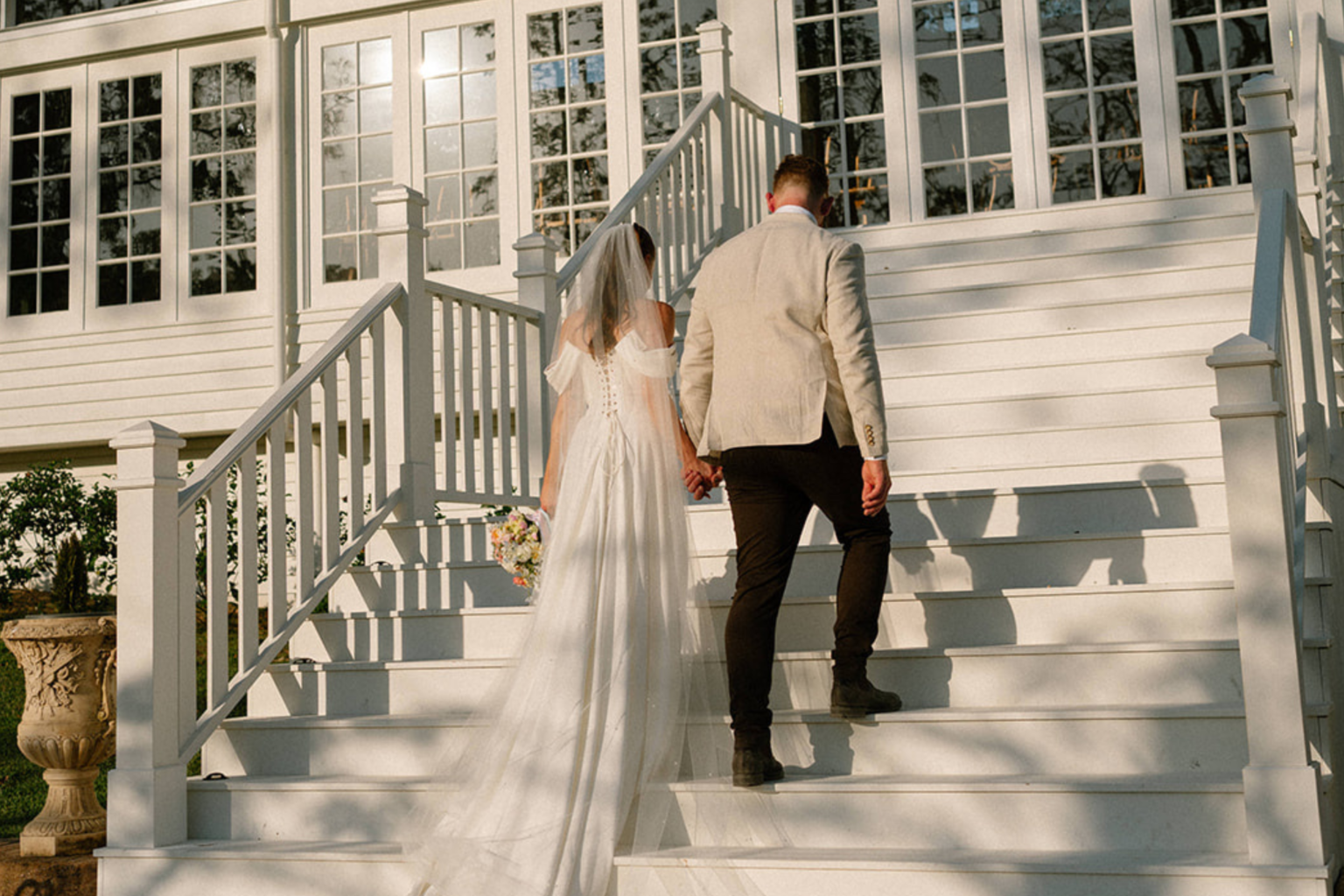 Bride and groom climbing the white staircase at Kwila Lodge