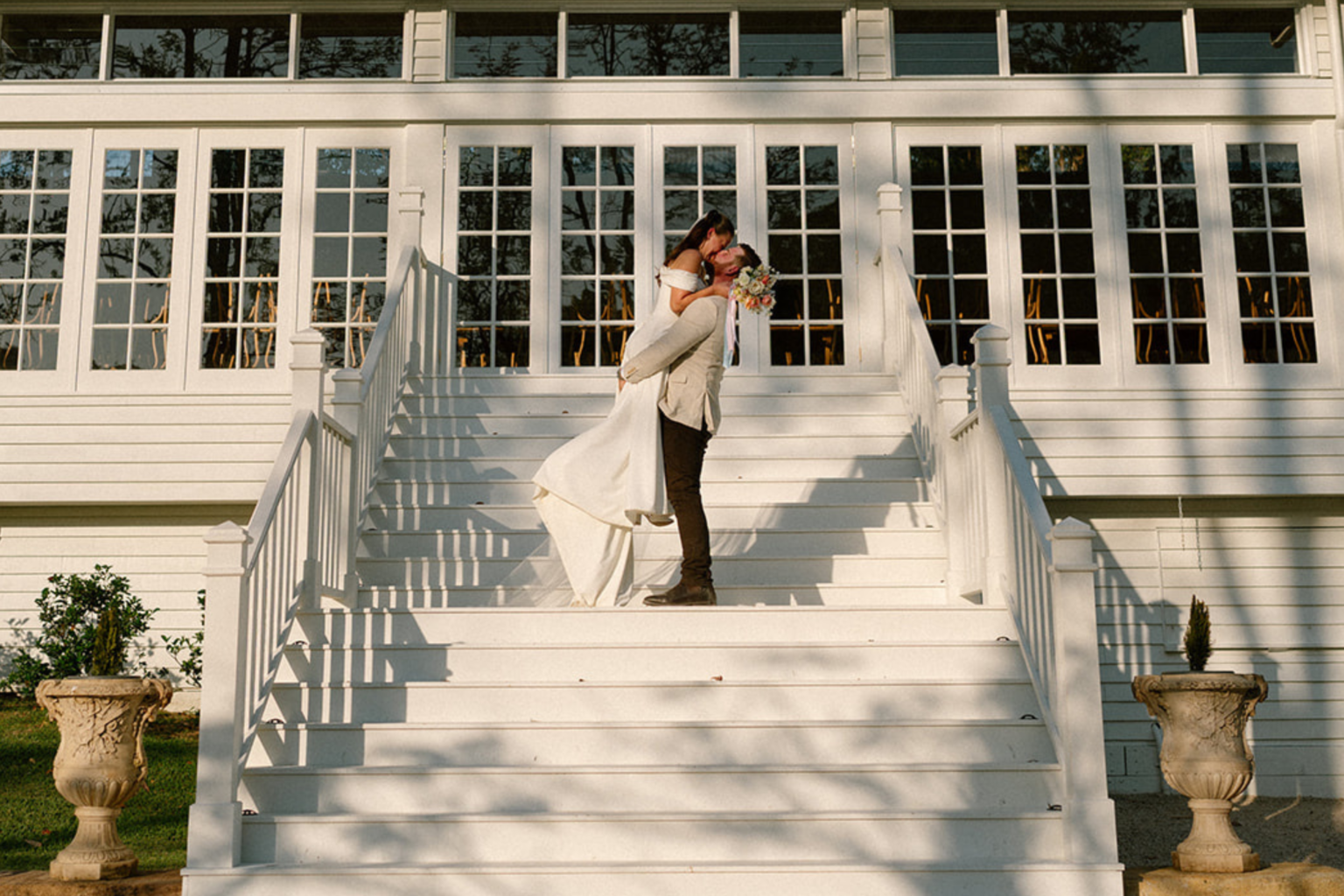 Groom lifting the bride on the white staircase at Kwila Lodge