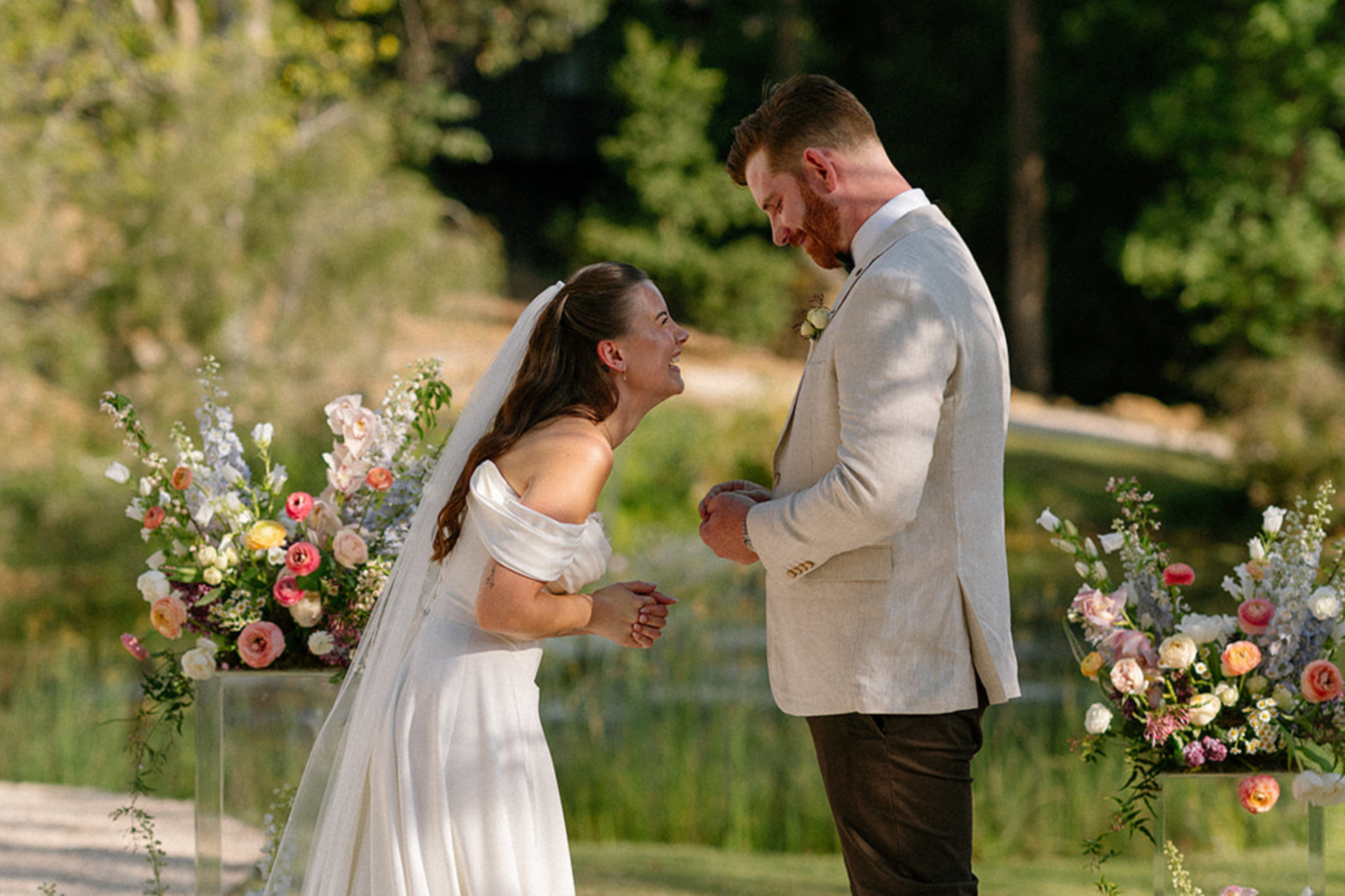 Bride laughing during the ceremony beside floral arrangements