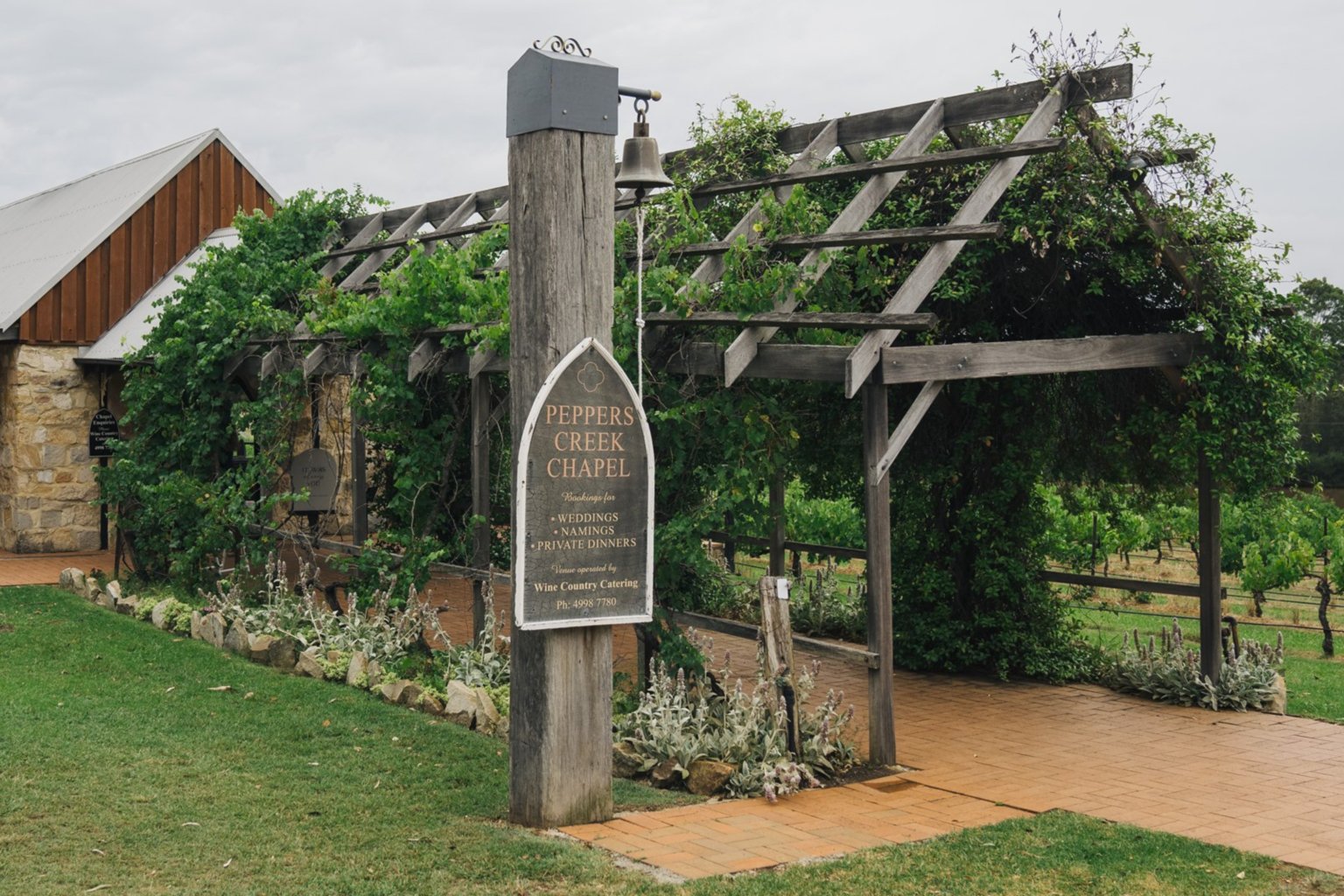 Vine-covered pergola and chapel sign at Peppers Creek