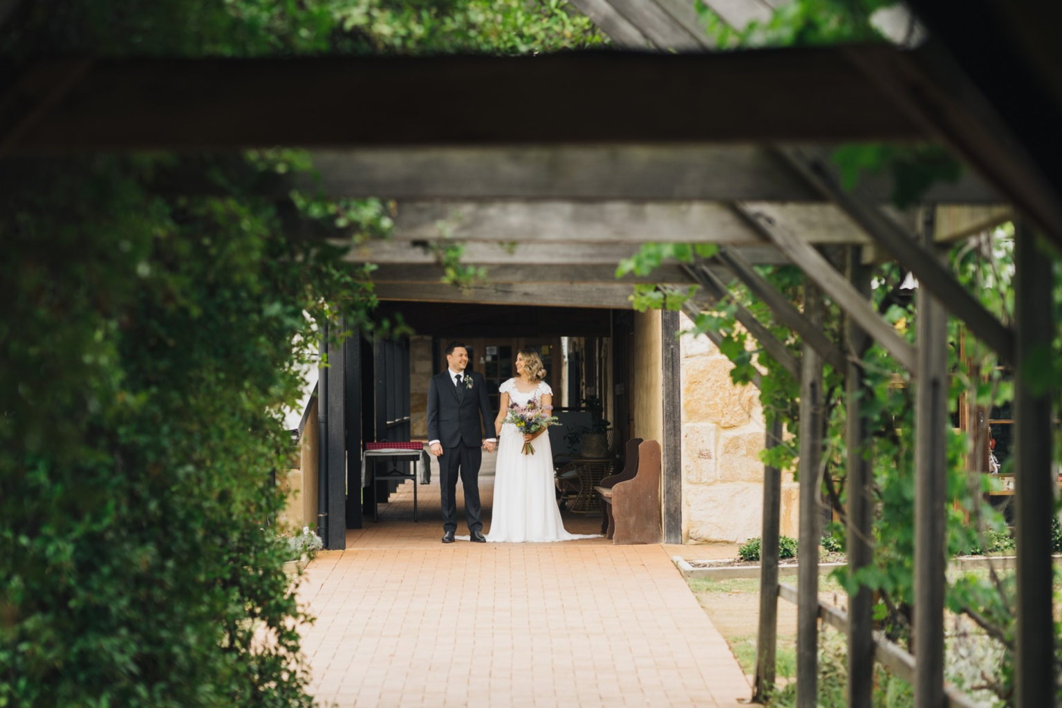 Couple standing beneath the timber pergola at Peppers Creek