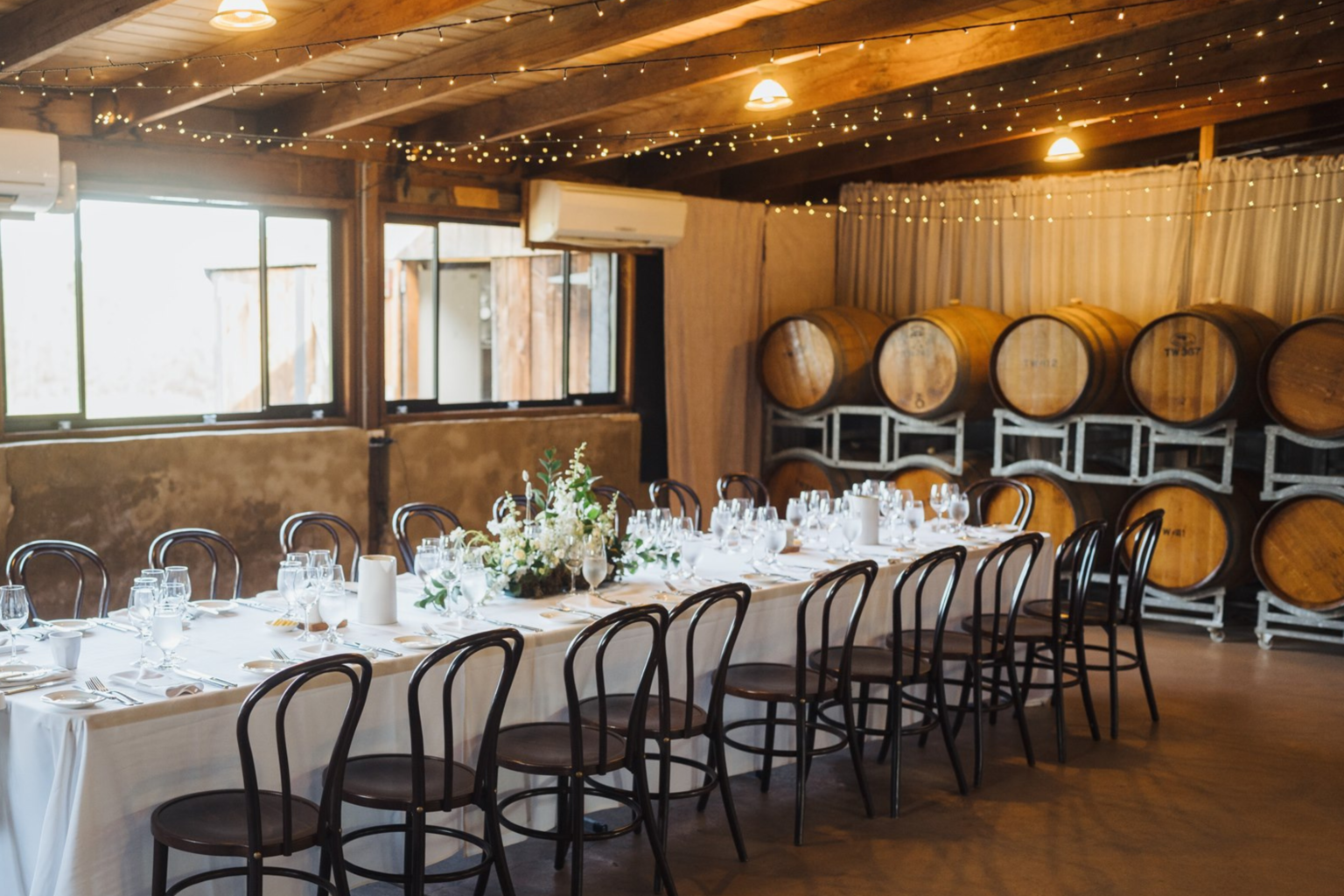 Long table set among wine barrels in the Barrel Room