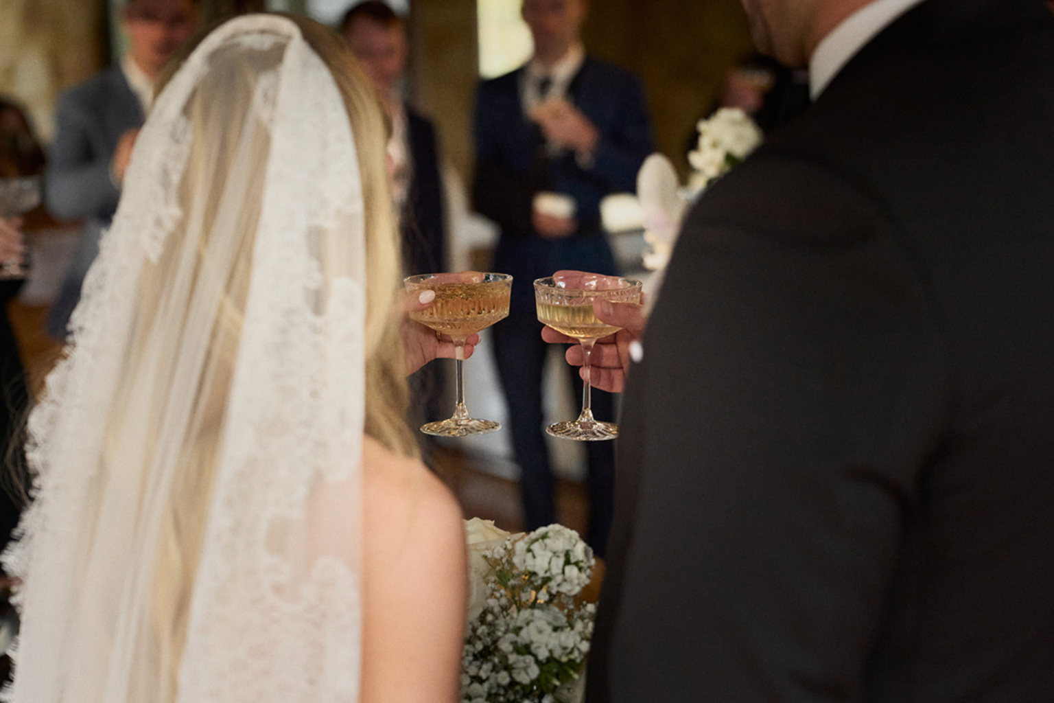 Couple clinking champagne glasses with guests behind