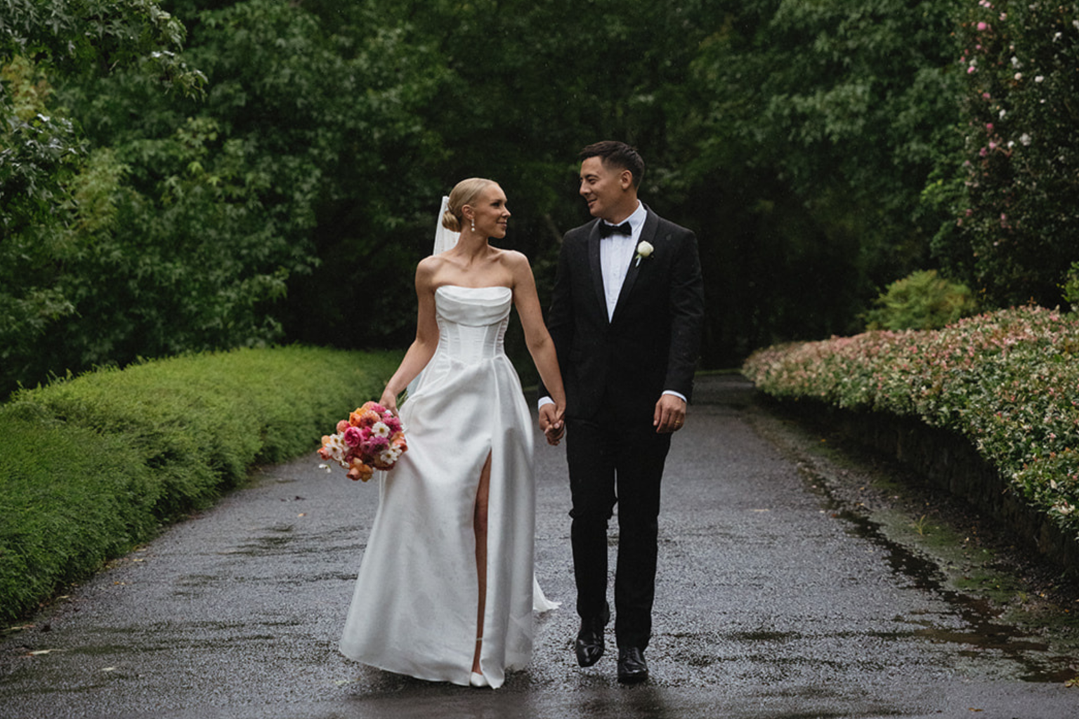 Couple smiling as they walk along a green garden path