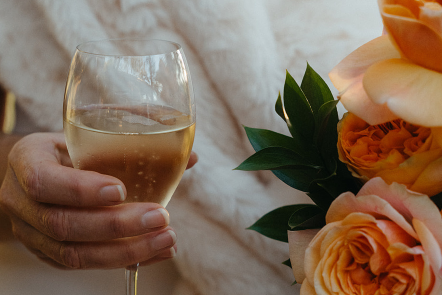 Glass of champagne beside orange garden roses