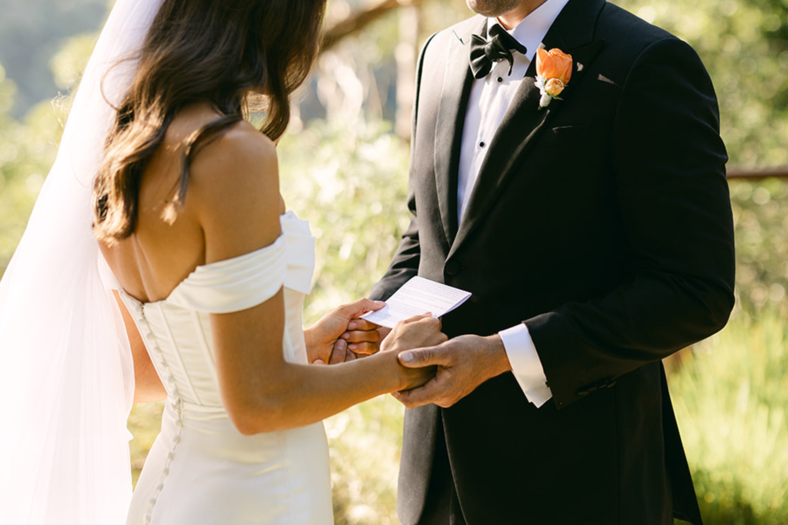 Couple holding hands as they read their vows