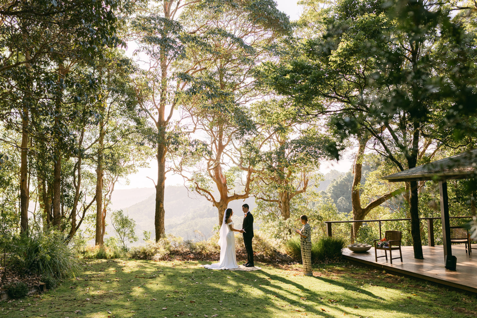 Couple exchanging vows on the lawn among tall trees