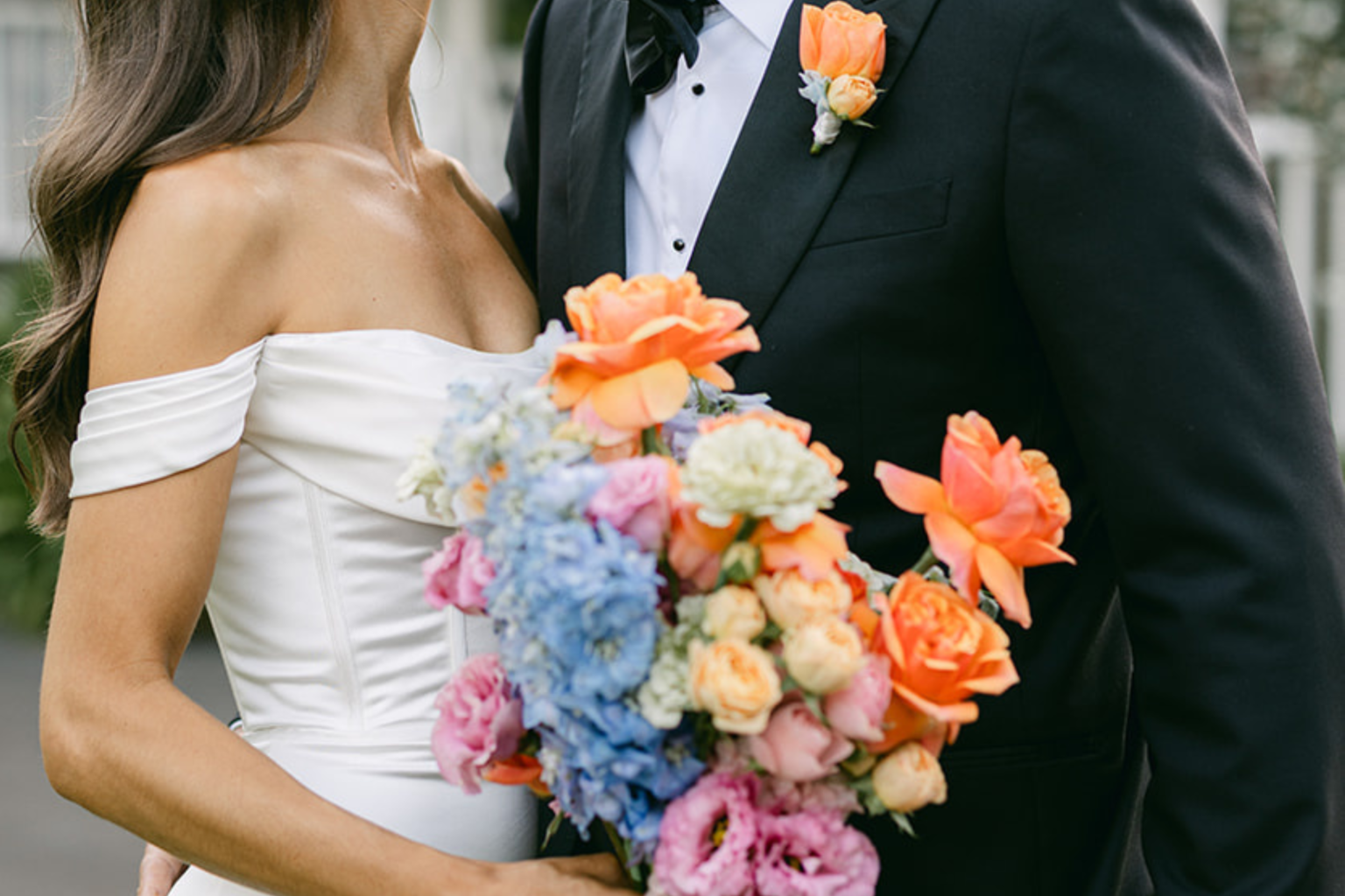 Bride holding a colourful bouquet with orange roses and blue hydrangea