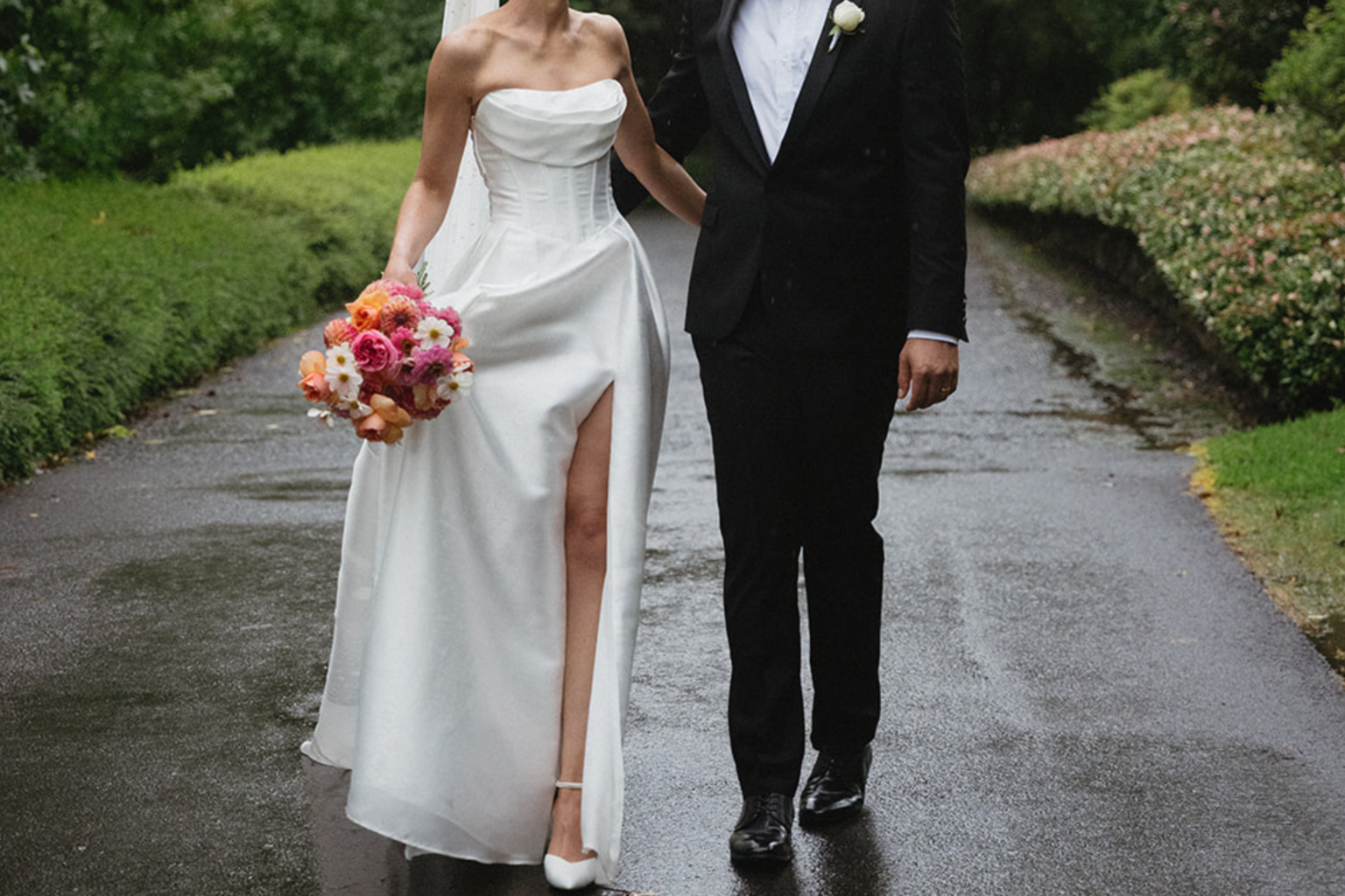 Couple walking down a rain-soaked garden path