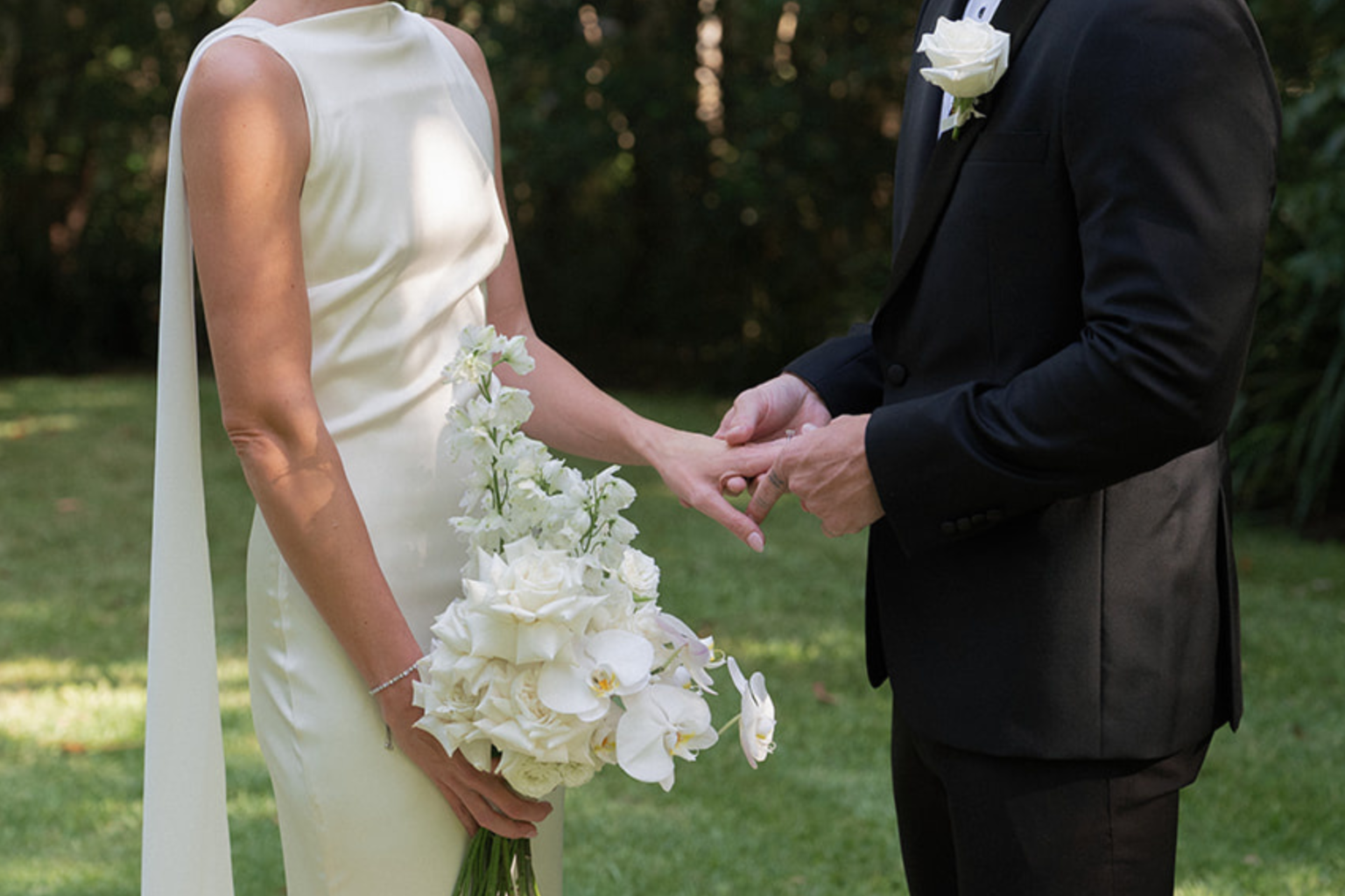 Couple holding hands as the bride holds white orchids