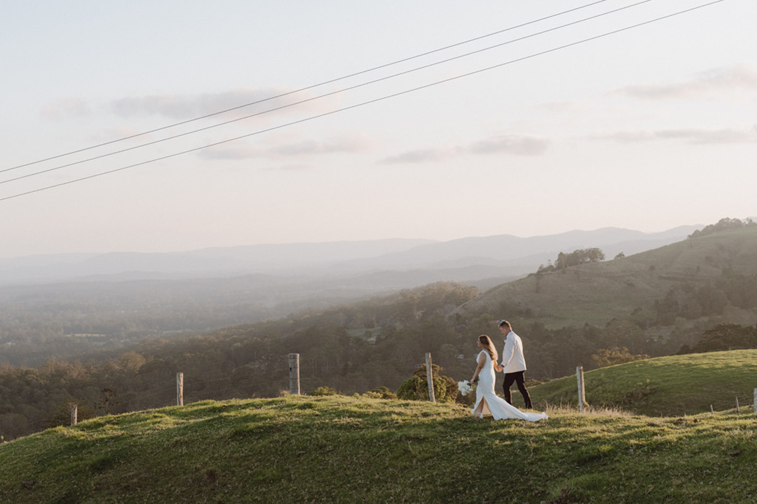 Couple on a grassy hilltop overlooking the hinterland at dusk
