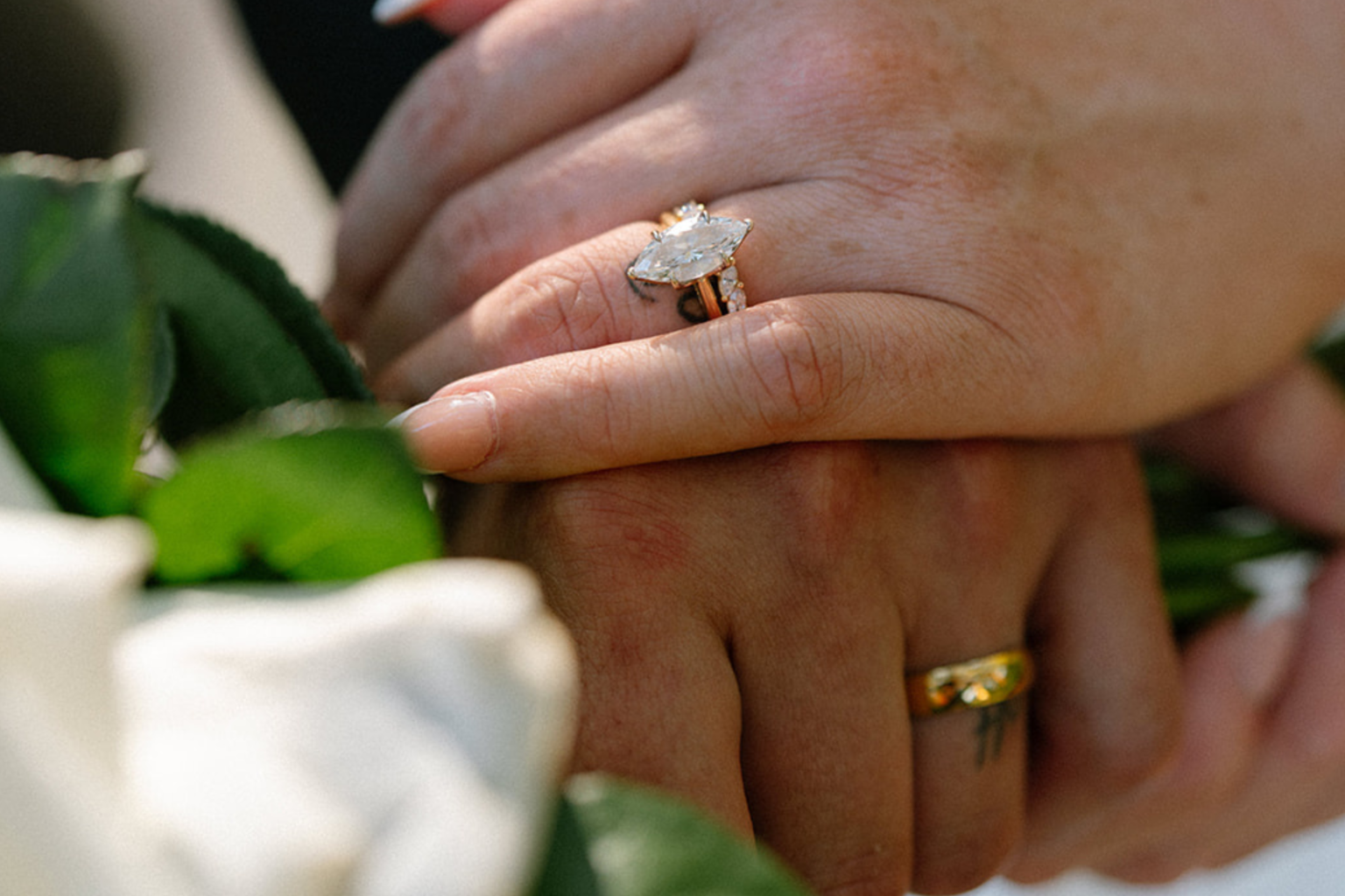 Close-up of the couple's hands and rings with white roses