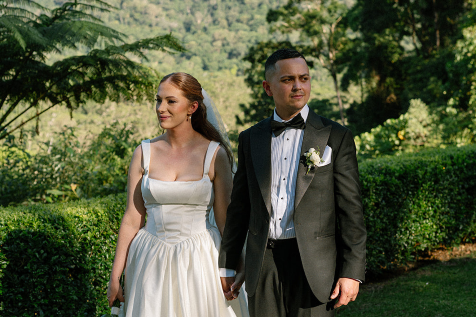Couple standing hand in hand among the tree ferns