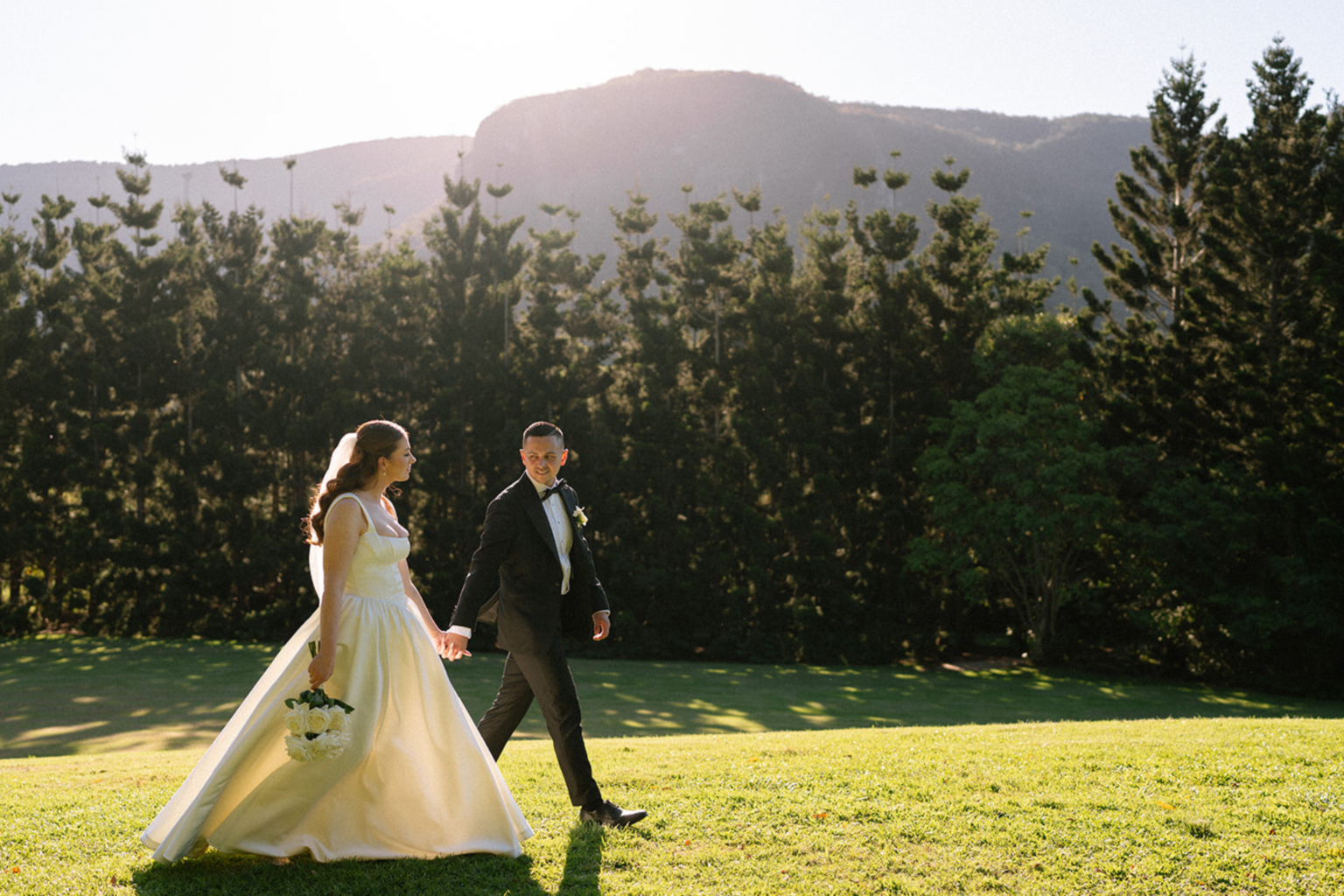 Bride and groom walking across the lawn below the escarpment