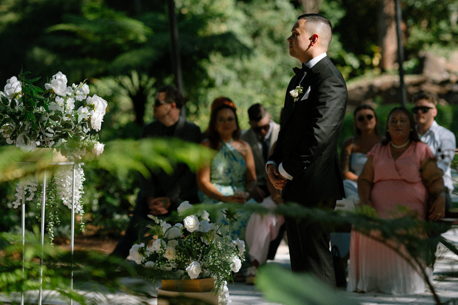 Groom waiting at the altar under The Fig Tree with guests seated